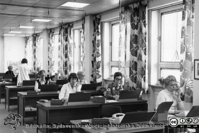 Telefonväxeln 1975/76
Påskrift på själva fotografiet: Lasarettet i Lund 16/5 1975. Påskrift på den kartong fotot monerats på: "MS-8.474. LL:s område norr: interiör. Telefonväxel 1976. På lasarettets telefonväxel arbetar 16 heltidsansällda telefonister, 6 vikarier samt en förestånderska. Man expedierar där 8500 inkommande samtal om dagen samt ca 3-400 utgående rikssamtal. Inom sjukhuset finns 1500 anknytningar. (MS-8474)." - Datum på själva fotot är rimligen mer trovärdigt än påskriften på kartongen det monterats på. Skillnaden är dock knappast signifikant. Jfr bilden 100911-013, tagen vid samma tillfälle. - Foto monterat på kartong.
Nyckelord: Kapsel 02 Regionarkivet;Telefon;Växel;Telefonister;Lasarettet;Lund;USiL,Universitetssjukhuset;Televäxel