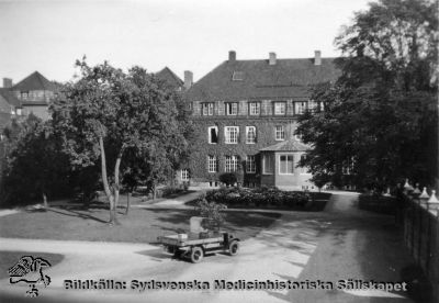 En av lasarettets första bilar, här på gården väster om Röntgeninstitutet omkring 1930
Påskrift: "Lasarettets första bil, omk. 1920 talet". Bilen syns framför dåvarande Röntgeninstitutet, byggt 1918, och är knappast samma bil som på bild SMHS2626_000_01, om än monterad på samma pappskiva. Bilden är tagen från 1929 års kök, så tidigt 1930-tal är mer sannolik datering.
Nyckelord: Kapsel 03;Regionarkivet;Lasarettet;Lund;Första;Lastbil;Röntgeninstitutet;1930-talet