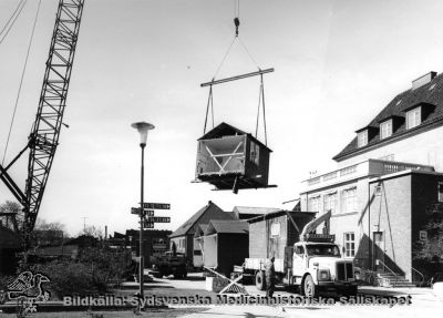 En barack lyfts i delar ut ur en av medicinklinikens innergårdar
En barack för ett forskningslaboratorium lyfts ut ur en av innergårdarna på dåvarande medicinska klinikens byggnad 1968. Fotografi monterat på styv kartong.
Baracken hade byggts i mitten på 1900-talet. Enligt uppgifter framkomna 2014 skall bilderna från baracklyftandet ha tagits 1968, samma år som medicinska kliniken flyttade in i centralblocket. Rimligen visar bildserien alltså hur baracken togs bort. Fil SMHS12291 kommer från samma negativ.
Nyckelord: Kapsel 03;Regionarkivet;Lasarettet;Lund;Medicin;Klinik;Barack;Forskning;Laboratorium