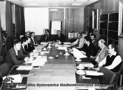 Landstingsdirektörens möte med sjukhusdirektörerna i Malmöhus Läns Landsting 1979-11-07. 
Landstingsdir. Bruno Wikfors (vid bordsänden). bitr. landstingsdi. Åke Haeggström (på ordf. vänstra sida), sjukhusdirektörerna Ewe Nilsson, Helsingborg, Jan Rosqvist (bitr. dir.), Helsingborg, Åke Asplund, Landskrona, P.O. Hallqvist, Lund (under tavlan till höger), Bernt Peterson, Orup, Olof Andersson, Trelleborg, Bengt Viterius, Ystad, sektionschef Kjell Bergström, Centralförv., sektionschef Lars-Åke Malmberg, PLR, sektionschef Ingvar Wiberg, Allm. (på ordförandens högra sida).
Nyckelord: Kapsel 04;Landstingsdirektör;Sjukhusdirektör;Landsting;Malmöhus;Län;1979