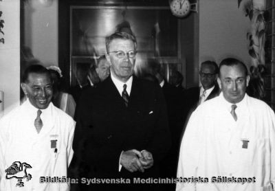 Hans Majestät Konung Gustav VI Adolf besöker radiologiska kliniken i Lund (Jubileumskliniken)
Besöket skedde efter invigningen av barnsjukhuset i Lund 1952. Till vänster radiologiska klinikens chef Göran Ebenius, och till höger överläkaren på avdelningen för onkologisk gynekologi, Gunnar Gorton. Lasarettsdirektör Arne Johansson skymtar i bakgrunden till höger, ur fokus. Samma bild som den senare funna SMHS06568.
Nyckelord: Kapsel 18;Lasarett;Lund;Radiologi;Radiologisk