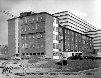 Radiologiska kliniken i Lund (tidigare Jubileumskliniken) från sydväst, efter tillbyggnad av högvoltsavdelningen 1963 - 1965 (närmast kameran). 
Omärkt bild. Originalfoto. Monterat. Det stora centralblocket som skymtar i bakgrunden stor färdigt 1968. Foto nära det året.
Nyckelord: Kapsel 18;Lund;Lasarett;Norra;Området