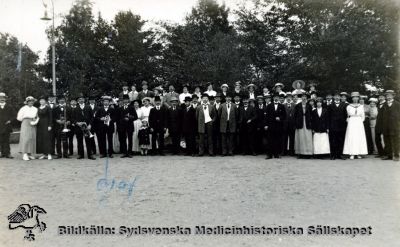 Personal från St Lars samlade i Folkets Park i Lund
Fotografiskt vykort med påskrift på baksidan: "Samling i Folkets park". "Olof Pe" finns markerad med blå kulspetspenna på kortets framsida. Vykortet saknar frimärke och poststämpel, och har alltså rimligen aldrig skickats någonstans. Vykort med samma fotografiska teknik har daterats till 1921, och personalens kladsel kan passa med det. Originalfoto. Ej monterat
Nyckelord: Kapsel 20;St Lars;Lund;Personal;Fest;Utflykt;Mentalvårdare;Skötare