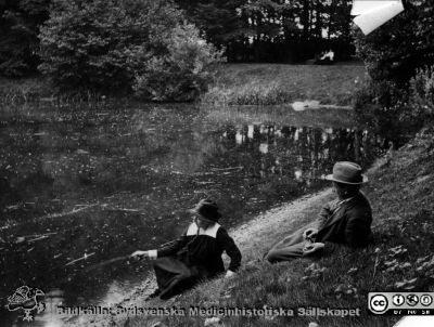 Vid stora dammen i St Lars-parken (senare igenlagd)
Kapsel 22 med bilder från St Lars i Lund. Påskrift: "Vid stora dammen". Originalfoto (skadat), rimligen från 1900-talets mitt eller första halva, bedömt efter kläderna. Ej monterat.
Nyckelord: Kapsel 22;St Lars;Lund;Park