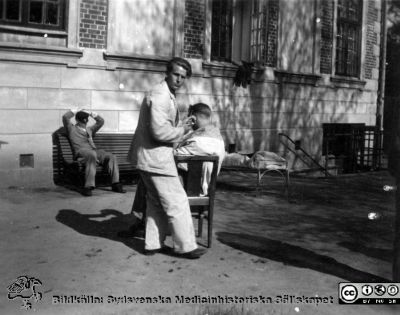 Skötare Böklin lipper håret på en patient år 1945
Kapsel 22 med bilder från St Lars i Lund. Påskrift: "Sköt. Böklin. Klippning å avd C II år 1945. S:t Lars". Originalfoto. Ej monterat
Nyckelord: Kapsel 22;St Lars;Lund;Personal;Skötare