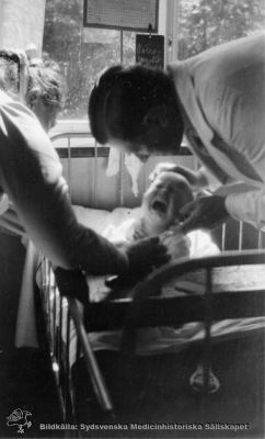 Gösta Lundh (1889 - 1948) undersöker ett barn
Foto troligen i början på 1930-talet. Bildkälla: Lena Lundh.
Nyckelord: Sjukhus; Barn;Undersökning;Läkare