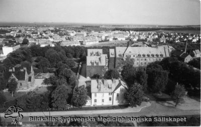 Lasarettet i Landskrona
Lasarettet i Landskrona.  Flygfoto över lasarettsområdet. Överläkarvillan till vänster, söder om sjukhuset. Ev. är bilden tagen från det vattentorn som står öster om lasarettsområdet. Idag (2011) är vattentornet ombyggt till privatbostäder. Öresund skymtar längst bort. Foto från Lena Lundh.
Nyckelord: Sjukhus; Exteriör; Flygfoto