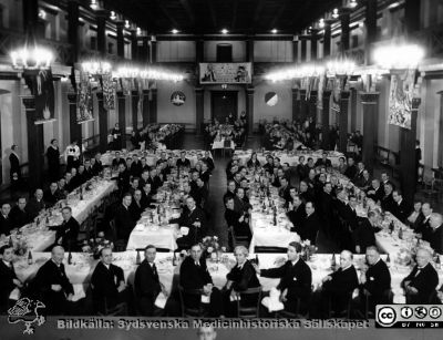 Galamiddag i Akademiska Föreningens Stora Sal 
Kapsel 25. Läkarsammankomsten m.m. Originalfoto Eriksson & Westerblad, Malmö. Galamiddag i Akademiska Föreningens Stora Sal före dess ombyggnad i mitten på 1900-talet. Det står "Stora Toddydagen" på banderollen i bakgrunden. Monterat
Nyckelord: Kapsel 25;Kongress;Lund;Universitet