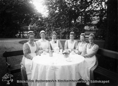 Sjuksköterskor i lasarettsparken 1902
Påskrift "Utbildning sjuksköterskor, Sophiasystrar i lasarettsparken 1902, Fr vä: Elin Linder, Teresa Löwenadler, Hedvig Olander, Barbro Svinhufvud, Inez Oom, Ebba Lagström. Fotot från Ebba Lagströms efterlämnade handlingar.
I databasen "Sveriges befolkning 1900" stavas Theresia Löwenadlers namn just så. Hennes mössa är utan svart band, och kanske var hon inte sofiasyster.
Nyckelord: SSSH;Sjuksköterskehem;Sköterska;Sverige;Södra;Kapsel 05;Elin;Linder;Teresa;Löwenadler;Hedvig;Olander;Barbro;Svinhufvud;Inez;Oom;Ebba;Lagström