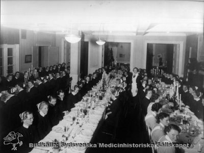 Fest på Södra Sveriges Sjuksköterskehem
Påskrift: Utbildning sjuksköterskor. Från SSSH i Lund. Ingen ytterligare påskrift. Omonterat foto.
Många av sköterskorna har hakband till sin mössa, vilket talar för att bilden är tagen senast i mitten av 1900-talet.
Nyckelord: Kapsel 05;Sköterska;Sjuksköterskehem;Sverige;Södra;SSSH;Fest;Gruppfoto;Personal;Foto;Omonterat