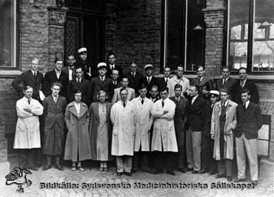 Medicinarkurs i patologi 1935
Påskrift: "Utbildning läkare VT 1935. Patologikursen." Flera ej namnsatta i de bakre leden, vänstra delen. Med delvis mycket svårtydd handstil:
"... Eriksson, Hederström, Stigbrandt, Ekelund, Radner, Lundström, Kullendorff?, Sartor
Forssman, Torstensson, Malmström, Prag, Werner, Thulin, Sträde, Fredholm, Gunnar Lindgren, N-A Nilsson, Edlen, Hedenquist, Lundh
Augrell (??), Elmqvist, Astrid Granstedt, Nina Svensson, Chefen, Moberg, Rudebeck."
"Chefen" är prof. Arvid Lindau.
Nyckelord: Kapsel 14;Utbildning;Läkare;Gruppfoto;1935;Patologi