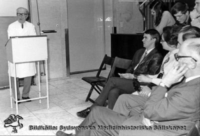 Helge B. Wulff föreläser i aulan på Malmö Allmänna sjukhus
Helge B. Wulff i talarstolen.
På första åhörarraden fr.vä.: dr. Bo Husberg, dr.Agneta Bjergel, doc. Stig Borgström och doc. Anders Wenckert. 
Foto på 1950-1960-talen, monterat på pappskiva, i dåtidens aula på Malmö Allmänna sjukhus.
Nyckelord: Kapsel 05;Utbildning;Läkare;Gruppfoto;Monterat;Aula;Malmö;MAS;Allmänna;Sjukhus;Helge;Wulff;Bo;Husberg;Agneta;Bjergel;Stig;Borgström;Anders;Wenckert