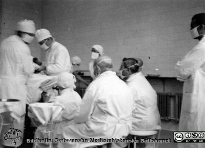 Kirurgisk operation i Lund sommaren 1936
Kapsel 28. Bild från kuvert märkt "Fotografier tagna av Elof Munck under studieåren på 1930-talet" och i innerkuvert märkt "Sommaren 1936 BB i Lund". Ingen påskrift på bilden. Operation pågår. Narkossköterskan droppar eter på öppen mask. Besökarna bär munskydd men inte mössa. Originalfoto. Omonterat.
Nyckelord: Kapsel 28;1930-talet;BB;Lund;Operation