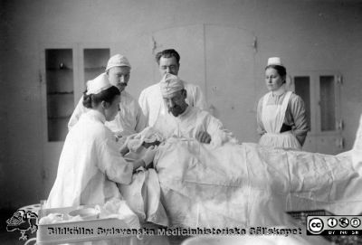 Professor Jacques Borelius opererar
Kapsel 29. Påskrifter: "Kirurgiska klinikens operation, hösten 1905. MS 5553. Prof. J. Borelius, Sven Johansson och Gustaf Petren. LL:s område, söder: interiör". Det är Borelius som opererar. Sven Johansson har mössa. Gustaf Petrén är nästan skymd av operatören. Originalfoto. Monterat
Nyckelord: Kapsel 29;Kirurgi;Operation;Narkos;Lund;Universitetssjukhus