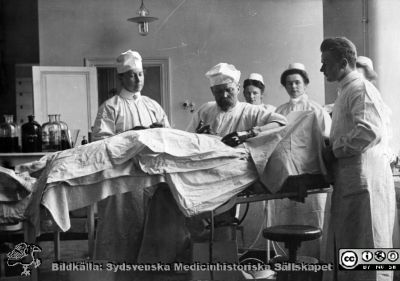 Professor Lennander i Uppsala opererar
Kapsel 30. Sjukhus i Sverige. Operationssalen, akademiska sjukhuset Uppsala 1906. Professor Lennander, doktor Levi Bergström, Syster Anna Myrsten, Syster Elin Axell, Syster Agnes Grip, Syster Elin ?. Namnen ovan nedskrivna av prof Gunnar Nyström. F.ö.se Sv. Läkarsällsk, Handl. Bd 26 1955 Häfte 2, sid 52. Originalfoto. Monterat.
Nyckelord: Kapsel 30;Operation;Kirurgi;Akademiska;Sjukhuset;Professor;Sköterska