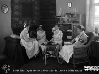 Sjuksköterskor i ett dagrum, kanske på ett sköterskehem?
Kapsel 30. Omärkt bild, rimligen från mitten av 1900-talet. Sköterskan längst till vänster SSSH-sköterskors uniform. De två i mitten bär armbindlar märkta U.A.S., dvs de har uniform från Uppsala Allmänna Sjukus. Originalfoto. Monterat
Nyckelord: Kapsel 30;Personal;Sköterska;Dagrum