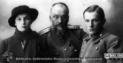 Generalläkare Jevgenij Sergejevitj Botkin med kvinna och ung man
Kapsel 30. Påskrift: " Bild 3, sid 87" och "Porträttfotografier". Reprofoto, rastrerat. Identifieringar av Mikael Dahlgren 2012: Tsarfamiljens livmedikus/hovmedikus från 1908 och fram till det bittra slutet. Botkin avrättades tillsammans med tsarfamiljen i Jekaterinburg 1918. Ynglingen är förmodligen en av hans tre söner  och kvinnan torde vara hustrun Olga. De skildes omkring 1910. Foto alltså före c:a 1910. Medaljer: Sankt Vladimirs orden och Saint Stanislaus orden.
Nyckelord: Kapsel 30;Porträtt