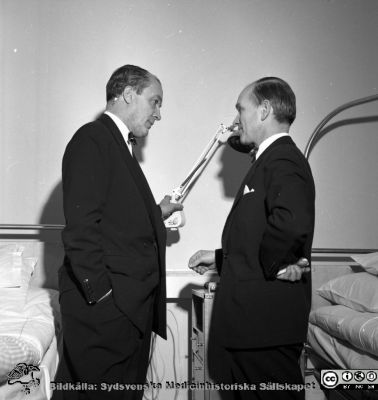 Sjukhusledningen på Malmö Allmänna sjukhus besöker en vårdavdelning. 
Album äldre neg. 1951-1958 MAS, från fotograf Björn Henrikssons samling. Kanske i samband med invigningn av bl.a. ögonklinikens nya hus 1961-01-21. Negativ.
Nyckelord: Malmö;1951-1958;Direktion;Sjukhusledning;Inspektion