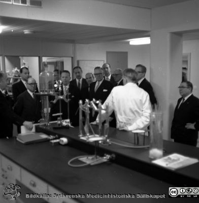 Sjukhusledningen på Malmö Allmänna sjukhus på besök i ett laboratorium.
Album äldre neg. 1951-1958 MAS, från fotograf Björn Henrikssons samling.  Kanske blodcentralen? Överläkaren och styresmannen Bengt Willert skymtar längst bak, längst. Kanske i samband med invigningn av bl.a. ögonklinikens nya hus 1961-01-21. Negativ.
Nyckelord: Direktion;Inspektion;Sjukhusledning;Malmö;Invigning;MAS