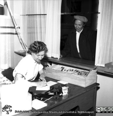 Reception vid en patientmottagning, 1950-talet, Malmö Allmänna Sjukhus. 
Album äldre neg. 1951-1958 MAS i lasarettsfotograf Björn Henrikssons samling. Omärkt bild. Kanske på kirurgiska kliniken.
Nyckelord: MAS;Malmö;Mottagning;Reception