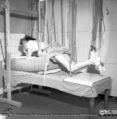 Patient på Malmö Allmänna Sjukhus upphängd i magläge. 
Pärm äldre neg. 1951-1958 MAS i lasarettsfotograf Björn Henrikssons samling. Rimligen foto från ortopediska kliniken.
Nyckelord: Kirurgi;Ortopedi;1950-talet;Malmö;Hängställning