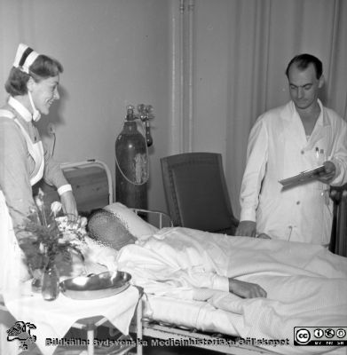  Malmö Allmänna Sjukhus, krirugiska kliniken. Dr Bengt Olow (kir. Klin.) vid patientens säng. 
Pärm äldre neg. 1951-1958 MAS, från fotograf Björn Henrikssons samling. Hemmets journal, kirurgen, sept 53.Negativ
Nyckelord: UMAS;MAS;Malmö;Allmänna;Sjukhus;Kirurgi;Vårdrum