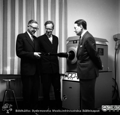Från invigningen 24/11 1961 av ögonklinikens nya byggnad i Malmö
Pärm neg. 1958-1962 MAS. Från fotograf Björn Henrikssons samling. Påskrift: "Ögon klin, invigning, 24/11-61". 
Doc Göte Öserlind förklarar den stora xenonlampefotokoagulatorn för prof. Jan Waldenström och doc. Karl Erik Hogeman. Från negativ
Nyckelord: UMAS;MAS;Malmö_;Allmänna;Sjukhus;Invigning;Ögon