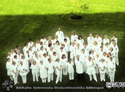  Personal från plastikkirurgiska kliniken. 
Album MAS 1987B i fotograf Björn Henrikssons samling. Plastik-kirurgen. Gruppbild, sept, 87. Magnus Åberg mitt i. Jan Wieslander på hans vänstra sida, vinkande. Håkan Brorson bakom, med kamera i svart axelband. På hans vänstra sida Björn Arnljots. I bakersta ledet nr 4 från höger Henry Svensson och nr 3 Emil Carlén.  Längst bak står Björn Palmer. Framför honom till höger i bilden står Birgitta Carlsson, dåvarande chefssekreterare/klinikassistent. Bredvid Emil Carlin står klinikens dåvarande kurator Marianne Egelborg, bredvid henne (längst ut) står Karin Ohlin, arbetsterapeut. Till vänster i civila kläder Claudie Forsberg, sjuksköterska, framför henne Clary Ljungdahl (senare Ekdahl ), klinikföreståndare och sedermera klinikadministratör. I raden framför henne aningen till höger Margaretha Karlsson, sekreterare. Från negativ
Nyckelord: UMAS;MAS;Malmö_;Allmänna;Sjukhus;Kirurgi;Plastik;Plastikkirurgi;Personal