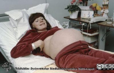 En höggravid kvinna visar glatt upp sin stora mage
KK förlossningen i Lund 1983. 
Nyckelord: Lund;Lasarett;Universitet;Universitetssjukhus;KK;Kvinnoklinik;obstetrik;gynekologi
