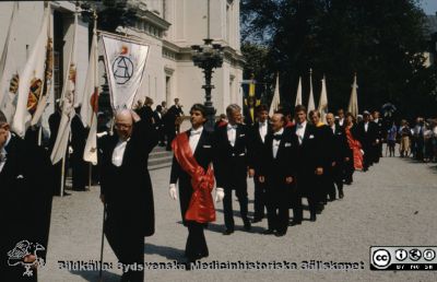 Promotionsprocession i Lund vid universitetshuset 1989
Doktorspromotion i Lund 1989. Statsminister Ingvar Carlsson (lång, ljushårig) strax bakom marskalken, på väg att promoveras till hedersdoktor  på samhällsvetenskapliga fakulteten. Mannen till höger om honom torde vara den andre hedersdoktorn Henry Mintzberg, företagsekonom från Kanada. Längre till vänster i bild jubeldoktorn Börje Kullenberg (med käpp). 
Nyckelord: Lund;Universitet;Promotion;Procession;Doktorspromotion;Hedersdoktor;Jubeldoktor;