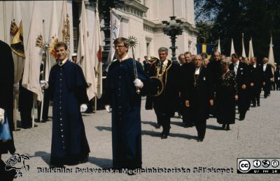 Processionen från universitetet vid doktorspromotion i Lund 1989 eller kanske 1988  
Efter de två  prestaverande pedellerna i blå långrockar ses honoratiores med univrektor Håkan Westling med rektorskedja och hatt tillsammans med biskop Per-Olof Ahrén. Mellan dem skymtar Kjell-Åke Modéer och till höger om honom Sverker Oredsson. Ahrén avgick som biskop 1992 och samma år avgick Håkan Westling som rektor. Sverker Oredsson var universitetsdirektör 1982-1990 och Kjell-Åke Modeér var Af´s ordförande 1983-1988. Fotot är troligen från 1989 eller kanske 1988. 
Nyckelord: Doktor;Doktorspromotion;Procession;Universitet;Promotion;Lund;Rector;Magnificus;Biskop;;