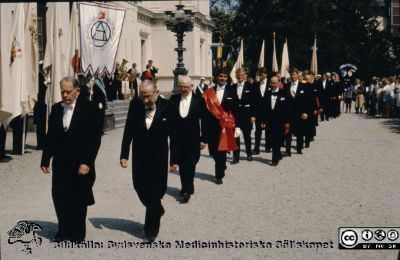 Processionen från universitetet vid doktorspromotion i Lund troligast 1989
De tre till vänster i bild bör vara jubeldoktorerna Ture Johannisson, Karl Erik Thomé och Börje Kullenberg. Bakom dem blivande hedersdoktorerna statsminister Ingvar Carlsson (lång, ljushårig) strax bakom marskalken, på väg att promoveras till hedersdoktor  på samhällsvetenskapliga fakulteten och mannen till höger om honom torde vara den andre hedersdoktorn Henry Mintzberg, företagsekonom från Kanada.
Nyckelord: Lund; Universitet; Promotion; Procession; Doktorspromotion; Hedersdoktor