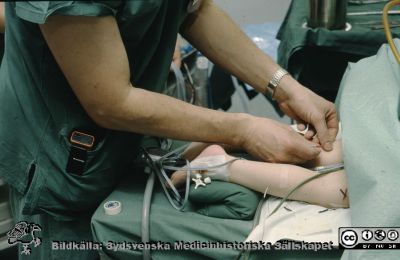 Förberedelse för neurokirurgiskt ingrepp på ett barn 1995
Ur låda med blandade diabilder från sjukhusfotograferna i Lund, 1970-, 1980- och 1990-talen. -95 Neurokirurgen.  Troligen insättning av en muskelelektrod för att kunna göra elektromyografi (EMG) under en rhitzotomi-operation i cauda equina pga spasticitet. 
Nyckelord: Lund;Lasarett;Universitet;Universitetssjukhus;Universsitetsklinik;Neurokirurgi;EMG