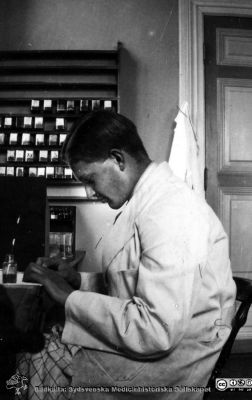 Fotoalbum tillägnat Professor Torsten Hellman från histologkursen 1929.
Fotoalbum tillägnat Professor Torsten Hellman med tacksamhet och vördnad från histologkursen 1929. Bildtext "Bengt Ehrenberg". 
Rimligen kursdeltagare  i kurslaboratoriet i färd med att göra mikroskopipreparat.
Bengt Ehrenberg (1909 - 1982) var amanuens på anatomiska institutionens histologiska avdelning 1930-1931 och i bakteriologi 1939. Han var sedan laboratorieföreståndare och exportchef på AB Ferrosan 1936 - 1959 samt direktör och chef för internationella avdelningen på AB Kabi i Stockholm sedan 1962. Han var administrativt aktiv i Medicinalstyrelsen och i Malmö kommun.
Nyckelord: Histologiska avdelningen;Anatomiska Institutionen;Medicinska fakulteten i Lund;Locus Medicus Lundensis;Universitet;Kurslaboration
