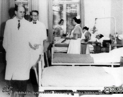 Rond på urologiska kliniken i Lund c:a 1960
Docent Lars-Erik Röhl och dr. Lennart Andersson går rond på urologiska avd. 1. I bakgrunden avdelningssköterskan Maj-Britt Jönsson och två sköterske-elever. Urologisk avdelning 1 på dåvarande kirurgiska byggnaden i Lund, någon gång nära år 1960. På bilden står: Urologisk avdelning urologi låda A 3:2.
Nyckelord: Lasarettet;Lund;Universitetssjukhuset;USiL;Kirurgisk;Urologisk;Klinik;Kapsel 11