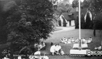 Reprofoto i samband med Lasarettet / vårdcentralen / länssjukhemmet i Hörbys 100-årsjubileum 1979-10-12.  
Midsommarafton i slutet på 1940-talet. I bakgrunden gamla tvätten med majstången framför. Till höger husmor Klara Vallin. Mitt på bilden står köksföreståndarinnan Ida Johansson vid ett bord och alla vi på gräset är personal från avdelningarna, operation, tvätt och ambulans.Bildkälla: ett fotoalbum på vårdcentralen i Hörby med bilder från lasarettet / vårdcentralen i Hörbys 100-årsjubileum 1979-10-12 (1).
Nyckelord: Lasarett;Hörby;Midsommar;Fester