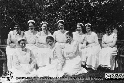 Undersköterskor på lasarettet i Helsingborg. 
Från en kontorspärm på Medicinhistoriska Museet i Helsingborg märkt "Äldre fotografier från med. + kir.klin.”. Foto troligast under 1900-talets två första decennier. Undersköterskorna. På marken t.v. Syster Sofia.
Nyckelord: Lasarettet;Helsingborg;Undersköterskor;Park