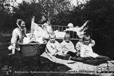 Syster Ida på kirurgiska kliniken med sina barnpatienter ute i lasarettsparken 
Från en kontorspärm på Medicinhistoriska Museet i Helsingborg märkt "Äldre fotografier från med. + kir.klin.”. Foto troligast under 1900-talets två första decennier. Syster Ida med sina patienter som alltid togs ut i parken på sommaren. Handskdriven notering: På sommaren sattes ett stor tält grässlänten mellan kirurgen och medicinen där de ...liga (?) patienterna evakuerades under vädring.
Nyckelord: Lasarettet;Helsingborg;Barnkliniken;Park;Vädring