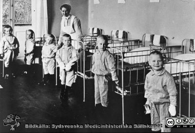 Syster Ida med sina patienter på barnsalen på kirurgiska avdelningen IV.
Från en kontorspärm på Medicinhistoriska Museet i Helsingborg märkt "Äldre fotografier från med. + kir.klin.”. Foto troligast under 1900-talets två första decennier. Syster Ida med sina patienter på barnsalen på kirurgiska avdelningen IV.
Nyckelord: Lasarettet;Helsingborg;Barn;Kirurgisk;Avdelning