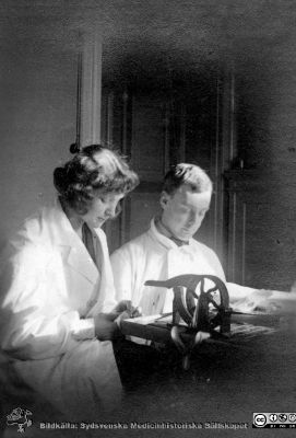 Bilder från histologiska avdelningen på anatomiska institutionen i Lund år 1923
Fotoalbum märkt 1923 på första bladet. Det innehåller bilder från dåvarande histologiska avdelningen på anatomiska institutionen i Lund på Biskopsgatan 7. Bildtext: Anna Christoffersson. Erik Järpe.  
De  förefaller hantera histologiska preparat i histologens kurslaboratorium. Det är okänt vad apparaten på bordet används till. 
Bildkälla Stiftelsen Locus Medicus Lundensis 250317. Fotograf okänd.
Nyckelord: Histologiska avdelningen;Anatomiska Institutionen;Locus Medicus Lundensis;Stiftelse;Medicinska fakulteten i Lund;Lunds universitet;Medicine studerande;Studenter;Kurslaboratorium