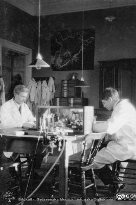 Album från histologikursen höstterminen 1925 i Lund
Album från histologikursen höstterminen 1925 i Lund. Bildtext: "Flit."  Rimligen elever på histologikursen. Notera gärna tavlan med ett vredgat monster på bortre väggen. Kanske ett tentamensodjur?? Foto i histologiska avdelningens kurslaboratorium i anatomiska institutionen på Biskopsgatan 7. Bildkälla Locus Medicus Lundensis 2025-03-17. Fotograf okänd.
Nyckelord: Elever;Medicine studerande;Histologiska avdelningen;Anatomiska Institutionen;Sydsvenska Medicinhistoriska Sällskapet;Medicinska fakulteten;Locus Medicus Lundensis;Lunds