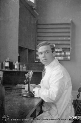Album från histologikursen höstterminen 1925 i Lund
Album från histologikursen höstterminen 1925 i Lund. Bildtext: "?."  Rimligen elev vid ett enkelt dissektionsmikroskop på histologikursen, men inte nybörjare som oftast inte hade ljus laboratoierock. Foto på i histologiska avdelningens kurslaboratorium på anatomiska institutionen på Biskopsgatan 7. Bildkälla Locus Medicus Lundensis 2025-03-17. Fotograf okänd.
Nyckelord: Elever;Medicine studerande;Histologiska avdelningen;Anatomiska Institutionen;Sydsvenska Medicinhistoriska Sällskapet;Medicinska fakulteten;Locus Medicus Lundensis;Lunds