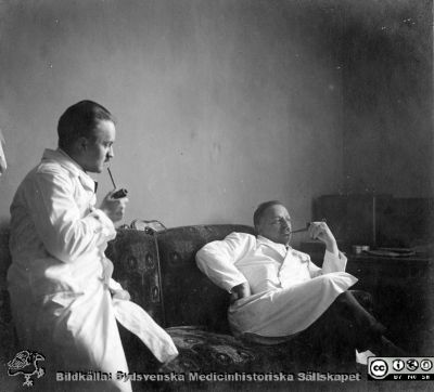 Thesaurus histologiae 1926
Fotoalbum på första bladet märkt 
"Thesaurus histologiae. 
thet är 
Een obiektiv beskrifning aff hendelser på then histologiska skåådebanan A.D. MDMXXVI. Med tacksamhet och vördnad överräckt av Kurs och amanuenser." på första bladet. 
Detta album innehåller bilder från histologiska avdelningen 
på anatomiska institutionen i Lund på Biskopsgatan 7. Bildtext: "Fig. 19b "Efter slaget." Troligast amanuensen Sture Siwe (1897 - 1966; senare professor i pediatrik i Lund) tillsammans med professor Torsten Hellman i soffan på dennes arbetsrum på på histologiska avdelningen på anatomiska institutionen.. 
Bildkälla Stiftelsen Locus Medicus Lundensis 250317. Fotograf okänd.
Nyckelord: Histologiska avdelningen;Locus Medicus Lundensis;Locus Medicus Lundensis;Medicinska fakulteten;Medicine studerande;Anatomiska Institutionen