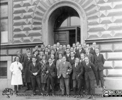 Thesaurus histologiae 1926
Fotoalbum på första bladet märkt 
"Thesaurus histologiae. 
thet är 
Een obiektiv beskrifning aff hendelser på then histologiska skåådebanan A.D. MDMXXVI. Med tacksamhet och vördnad överräckt av Kurs och amanuenser." . 
Detta album  innehåller bilder från histologiska avdelningen 
på anatomiska institutionen i Lund på Biskopsgatan 7. Bildtext: "Fig. 21 = Full salut!." Kursfoto av nöjda elever på entrétrappan till anatomiska institutionen efter avklarad tentamen. Troligast kursamanuensen Sture Siwe i vit laboratorierock till vänster i bilden. 
Bildkälla Stiftelsen Locus Medicus Lundensis 250317. Fotograf okänd.
Nyckelord: Histologiska avdelningen;Locus Medicus Lundensis;Locus Medicus Lundensis;Medicinska fakulteten;Medicine studerande;Anatomiska Institutionen;Kursfoto