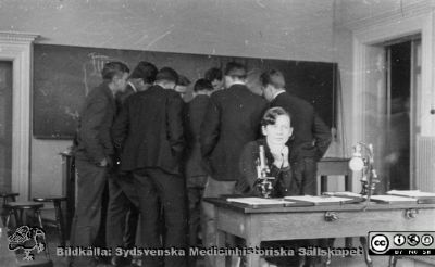 Fotoalbum tillägnat Professor Torsten Hellman 1929
Fotoalbum tillägnat Professor Torsten Hellman med tacksamhet och vördnad från histologikursen 1929. Sociala delen i detta album. Bildtext saknas. Studenterna flockas runt något intressant i föreläsningssalen. En sitter vid sitt mikroskop och tänker på något annat. Kanske Nelly Håkansson?
Bildkälla Stiftelsen Locus Medicus Lundensis 250317. Sydsvenska Medicinhistoriska Sällskapet / SMHS. Fotograf okänd.
Nyckelord: Anatomiska Institutionen;Histologiska avdelningen;Mikroskopering;Medicinska fakulteten i Lund;Locus Medicus Lundensis;Universitetet i Lund