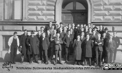 Fotoalbum tillägnat Professor Torsten Hellman från lärjungar under Kursen 1924 - 25
Fotoalbum tillägnat Professor Torsten Hellman från lärjungar under Kursen 1924 - 25. Kursfoto på entretrappan till anatomiska institutionen. Troligen står det en amanuens i vit laboratorierock till vänster. Möjligen står  professor Hellman som nr 3 från vänster, med hatt på huvudet. Ingen bildtext.
Bildkälla Stiftelsen Locus Medicus Lundensis 250317. Fotograf okänd.
