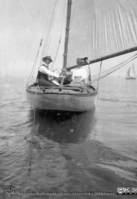 Ett medelålders par i segelbåt i svag vind på okänt vatten.
Bild 71 i Anna Landelius efterlämnade fotoalbum. Hon var  husmor på Lasarettet i Lund från 1924. Ingrid Frennhoff (f. 1944) hade övertagit detta album efter sin morfar som i sin tur tagit hand om det efter sin syster husmor Anna på Lasarettet i Lund. Detta album är en gåva från Ingrid Frennhoff till Sydsvenska Medicinhistoriska Sällskapet  i Lund.

Nyckelord: Segelbåt;Stiltje