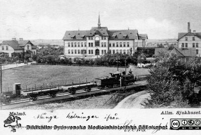 Vykort O. E. K. 8026 från Saumuel Bengtssons missionsbokhandel med bild av Malmö Allmänna Sjukhus nära sekelskiftet 1900. 
Ett godståg går på Malmö-Ystads Järnvägs spår alldeles hitom sjukhuset. Kortet är adresserat till Fröken Elisabeth Gyllenberg, Allmänna Sjukhuset, Södervärn (rimligen en dotter till sjukhusets syssloman E. A. Gyllenberg). Vykortets poststämpel är inte tolkningsbar, men den felaktiga postadressen (Södervärn i stället för Malmö och ingen gatuadress) pekar på att kortet skickats inom Malmö eller i varje fall Skåne.
Foto från samling funnen på KK i Lund hösten 2016 och tillvaratagen av en sekreterare där i samband med att hon gick i pension och överlämnat den till Sydsvenska Medicinhistoriska Sällskapet utan att ange sitt namn. 
Nyckelord: Malmö;Allmänna;Sjukhus;MAS;Järnväg;Fasad;Exteriör;Vykort