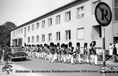 Pojkorkester i dansk paraduniform framför dåvarande röntgenavdelningens byggnad  (nybyggd 1942) på Malmö Allmänna Sjukhus.
 Foto före högertrafikens införande, troligen 1950-talet, kanske i samband med invigningen av aulan 1954 eller 100-årsjubileet 1957?
Foto från samling funnen på KK i Lund hösten 2016 och tillvaratagen av en sekreterare där i samband med att hon gick i pension och överlämnat den till Sydsvenska Medicinhistoriska Sällskapet utan att ange sitt namn. 
Nyckelord: Malmö;MAS;Allmänna;Sjukhus;Röntgen;Avdelning;Parad;Pojkorkester