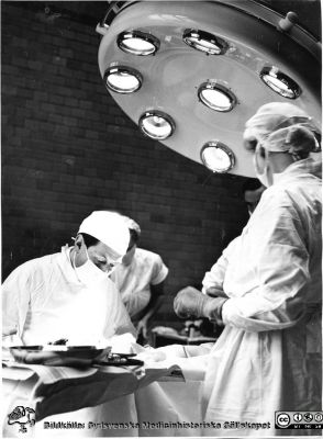 Docent Hogeman på plastikkirurgiska kliniken i Malmö opererar 1953. 
Syster Rut assisterar.
Foto från samling funnen på vinden på KK i Lund hösten 2016 och tillvaratagen av sekreteraren Elisabet Gyllander där i samband med att hon gick i pension och överlämnat den till Sydsvenska Medicinhistoriska Sällskapet. 
Nyckelord: UMAS;Malmö;Plastikkirurgisk;Klinik;Universitet;Universitetssjukhus;Allmänna;Sjukhus;Universitetssjukhus